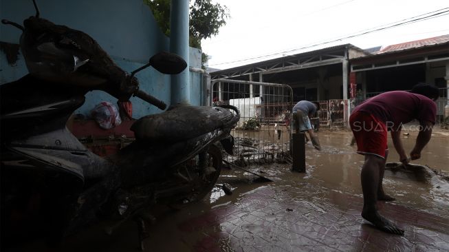 Warga membersihkan rumahnya dari endapan lumpur di Perumahan Pondok Mitra Lestari, Bekasi, Jawa Barat, Jumat (3/1). [Suara.com/Angga Budhiyanto]