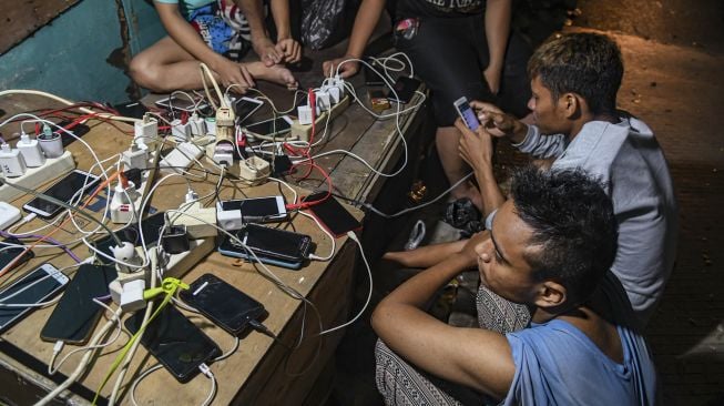 Warga melakukan pengisian daya untuk telepon genggamnya saat banjir melanda di kawasan Kembangan, Jakarta Barat, Kamis (2/1). [ANTARA FOTO/Muhammad Adimaja]