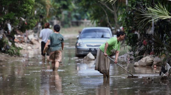 Warga membersihkan endapan lumpur di Perumahan Pondok Mitra Lestari, Bekasi, Jawa Barat, Jumat (3/1). [Suara.com/Angga Budhiyanto]