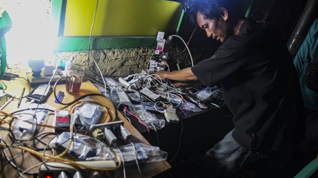 Warga melakukan pengisian daya untuk telepon genggamnya saat banjir melanda di kawasan Kembangan, Jakarta Barat, Kamis (2/1). [ANTARA FOTO/Muhammad Adimaja]