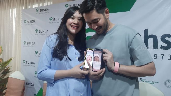 Syahnaz Sadiqah dan Jeje Govinda menunjukkan foto anak kembarnya kepada wartawan. [Evi Ariska/Suara.com]