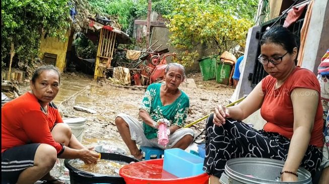 Sejumlah ibu-ibu di Kampung Pulo, Jakarta Timur gotong royong membersihkan peralatan rumah tangga usai dilanda banjir. (Suara.com/M Yasir)