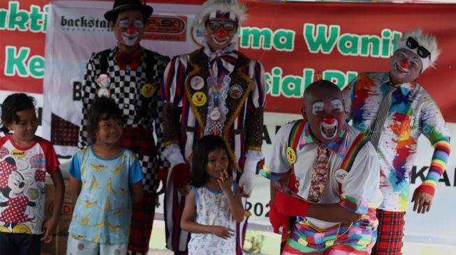 Sejumlah badut yang tergabung dalam komunitas Aku Badut Indonesia (ABI) menghibur anak-anak di pengungsian korban banjir Komplek IKPN Bintaro, Pesanggrahan, Jakarta Selatan, Minggu (5/1). [Suara.com/Angga Budhiyanto]