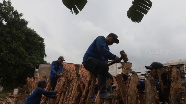 Petugas Sudin Sumber Daya Air Jakarta Selatan membangun tanggul sementara Kali Pesanggrahan yang jebol di Bintaro, Pesanggrahan, Jakarta Selatan, Minggu (5/1). [Suara.com/Angga Budhiyanto]