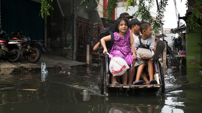 Pengayuh becak membawa penumpang menerobos banjir di Kawasan Teluk Gong, Penjaringan, Jakarta Utara, Sabtu (4/1). [Suara.com/Alfian Winanto]