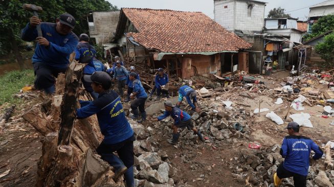 Petugas Sudin Sumber Daya Air Jakarta Selatan membangun tanggul sementara Kali Pesanggrahan yang jebol di Bintaro, Pesanggrahan, Jakarta Selatan, Minggu (5/1). [Suara.com/Angga Budhiyanto]