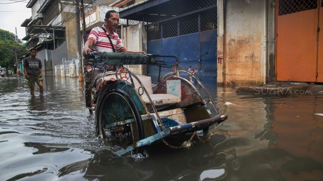 Pengayuh becak malang melintang menerobos banjir untuk mencari penumpang di Kawasan Teluk Gong, Penjaringan, Jakarta Utara, Sabtu (4/1). [Suara.com/Alfian Winanto]