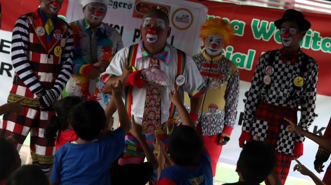 Sejumlah badut yang tergabung dalam komunitas Aku Badut Indonesia (ABI) menghibur anak-anak di pengungsian korban banjir Komplek IKPN Bintaro, Pesanggrahan, Jakarta Selatan, Minggu (5/1). [Suara.com/Angga Budhiyanto]