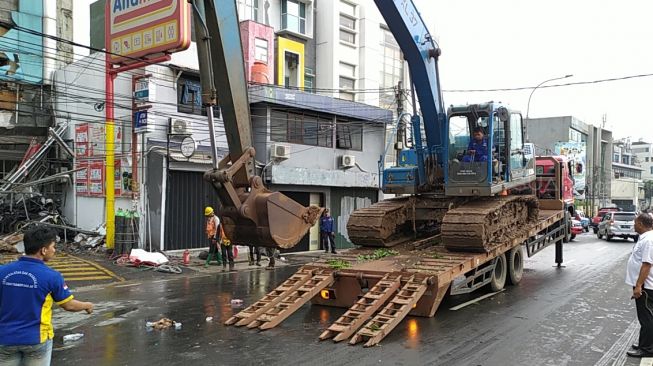 Ruko minimarket Alfamart di Jalan Letjen Katamso, Slipi, Jakarta Barat yang ambruk pada Senin (6/1/2020) pagi mulai diratakan. (Suara.com/Tyo)