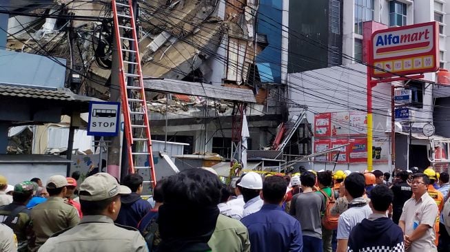 Warga melihat Ruko Alfamart yang roboh di Slipi, Jakarta Barat, Senin (6/1). [Suara.com/Stephanus Aranditio]