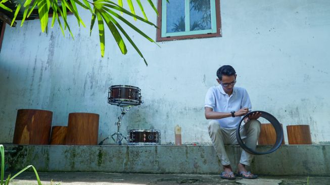 Tiar sedang melapisi snare drum dengan cat minyak agar terlihat lebih halus dan rapi. [Suara.com/Anang Firmansyah]