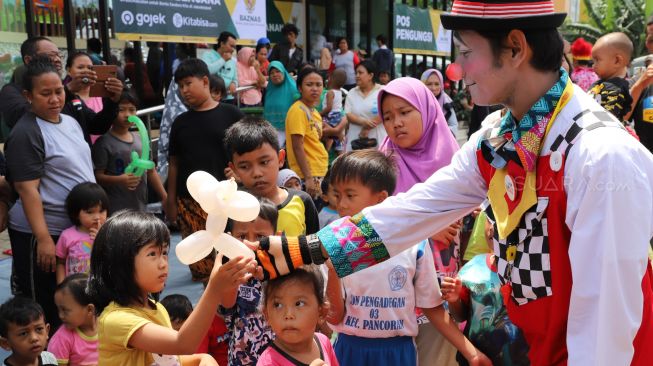 Aksi para badut komunitas Aku Badut Indonesia (ABI) saat menghibur anak-anak korban banjir di posko pengungsian bencana banjir Gor  Pengadegan, Jakarta Selatan, Selasa (07/01).(suara.com/Alfian Winanto).