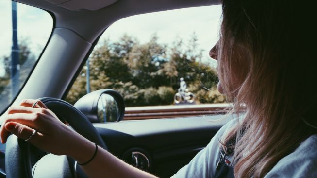 Ilustrasi perempuan mengendarai mobil. (Unsplash/Samuel Foster)