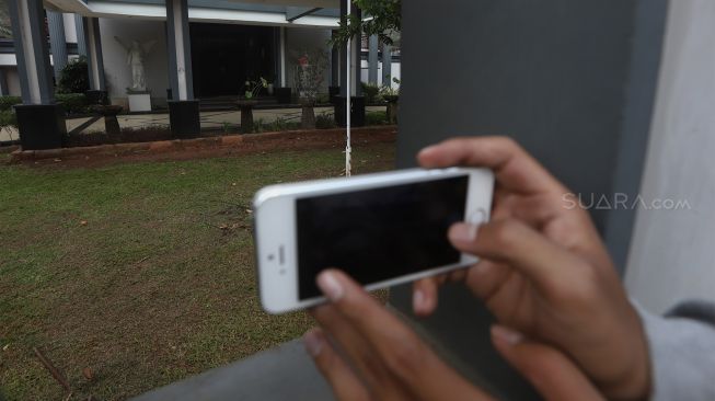 Seorang wartawan mengambil gambar suasana rumah orang tua Reynhard Sinaga di Jalan Dahlia, Pancoran Mas, Depok, Jawa Barat, Selasa (7/1). [Suara.com/Angga Budhiyanto]