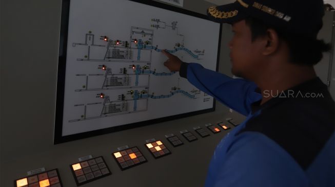 Petugas Dinas Sumber Daya Air (SDA) Aliran Tengah melakukan pengecekan panel mesin pompa air di Rumah Pompa Waduk Pluit, Jakarta Utara, Rabu (8/1). [Suara.com/Angga Budhiyanto] 