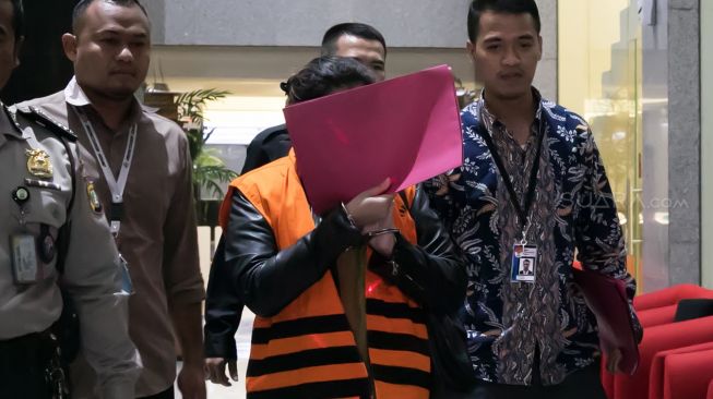 Tersangka mantan anggota Bawaslu Agustiani Tio Fridelina mengenakan rompi tahanan usai menjalani pemeriksaan di gedung KPK, Jakarta, Jumat (10/1) dini hari.[Suara.com/Alfian Winanto]
