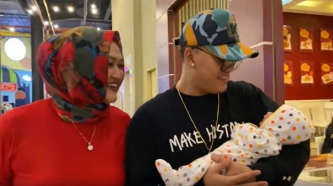 Rizky Febian terlihat bahagia menggendong bayi Lina Jubaedah, yang juga adik tirinya. [YouTube]