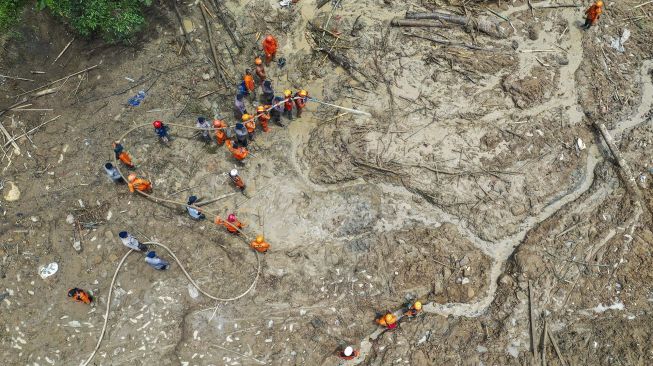 Foto udara anggota tim SAR gabungan menggunakan alat penyemprot air untuk melakukan pencarian korban tanah longsor dan banjir bandang yang masih belum ditemukan di Kampung Sinar Harapan, Desa Harkat Jaya, Kecamatan Sukajaya, Kabupaten Bogor, Jawa Barat, Sabtu (11/1). [ANTARA FOTO/Galih Pradipta]