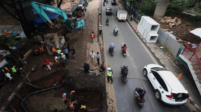 Petugas melakukan proses perbaikan jalan yang amblas di Jalan Daan Mogot, Kota Tangerang, Banten, Senin (13/1). [Suara.com/Angga Budhiyanto]