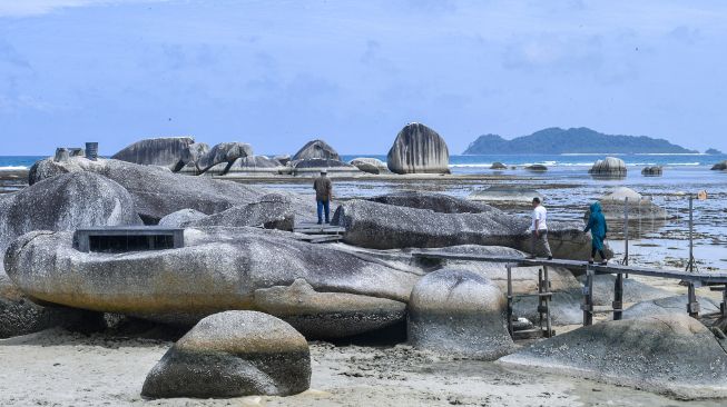 Sejumlah pengunjung melintas diantara bongkahan batu granit di Alif Stone Park, Desa Sepempang, Kabupaten Natuna, Provinsi Kepulauan Riau, Senin (13/1). [ANTARA FOTO/M Risyal Hidayat]