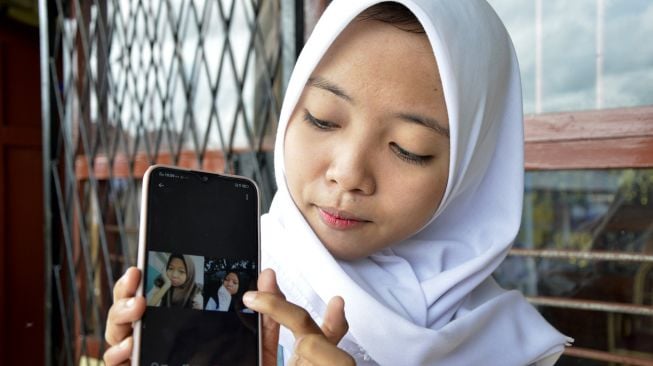 Nabila Azzahrah (16) memperlihatkan foto saudara kembarnya yang ditemuinya melalui media sosial twitter, di Kabupaten Gowa, Sulawesi Selatan, Senin (13/1). [ANTARA FOTO/Abriawan Abhe]