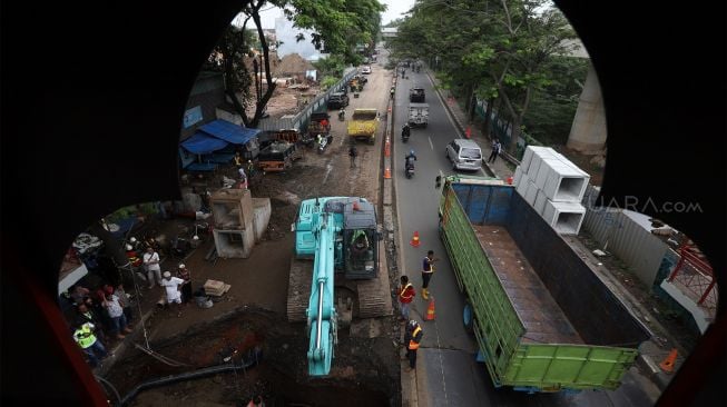 Petugas melakukan proses perbaikan jalan yang amblas di Jalan Daan Mogot, Kota Tangerang, Banten, Senin (13/1). [Suara.com/Angga Budhiyanto]