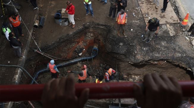 Petugas melakukan proses perbaikan jalan yang amblas di Jalan Daan Mogot, Kota Tangerang, Banten, Senin (13/1). [Suara.com/Angga Budhiyanto]