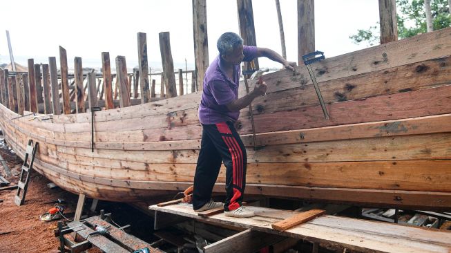 Pekerja menyelesaikan pembuatan kapal motor di Desa Tanjung, Natuna, Kepulauan Riau, Selasa (14/1). [ANTARA FOTO/M Risyal Hidayat]