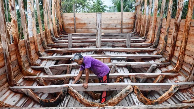 Pekerja menyelesaikan pembuatan kapal motor di Desa Tanjung, Natuna, Kepulauan Riau, Selasa (14/1). [ANTARA FOTO/M Risyal Hidayat]