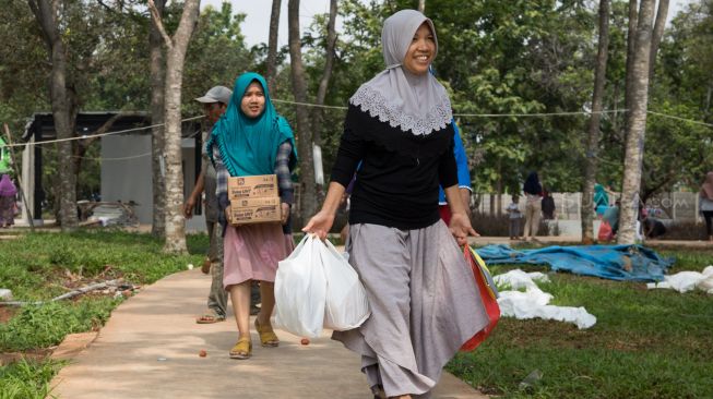 Warga usai berbelanja pangan murah di RPTRA Ranggon Kusuma Baru, Pondok Ranggon, Jakarta Timur, Selasa (14/01). [Suara.com/Alfian Winanto]