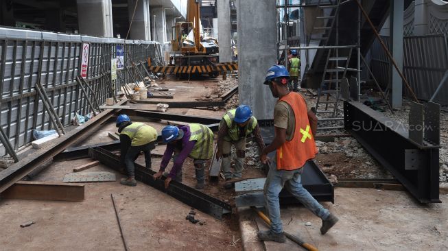 Pekerja menyelesaikan proyek jembatan layang integrasi antara Stasiun MRT ASEAN dengan Halte Centrale Stichting Wederopbouw (CSW) koridor 13 di Jakarta, Selasa (14/1). [Suara.com/Angga Budhiyanto]