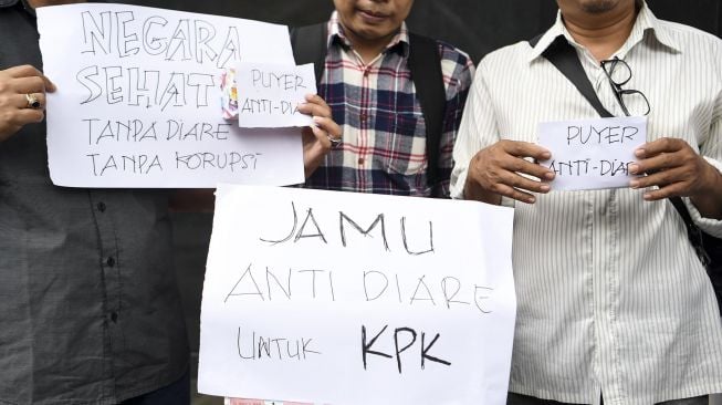 Sejumlah pegiat antikorupsi yang tergabung dalam koalisi masyarakat sipil menggelar aksi sebelum menyerahkan jamu antidiare di gedung KPK, Jakarta, Rabu (15/1). [ANTARA FOTO/Hafidz Mubarak] 
