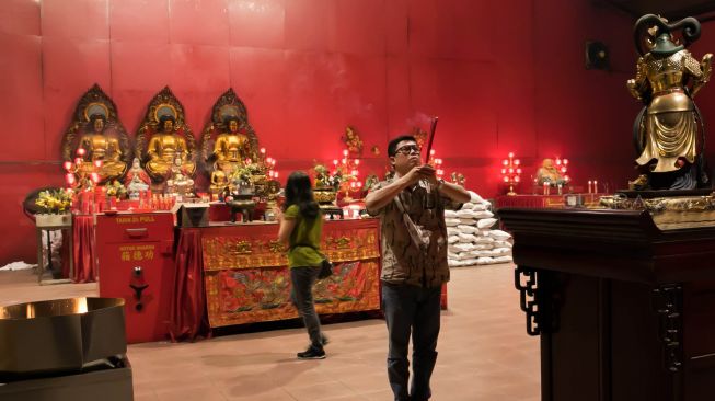 Para Jemaat yang sedang berdoa di Vihara Dharma Bhakti, Glodok, Jakarta Barat, Selasa (14/01).  [Suara.com/Alfian Winanto]
