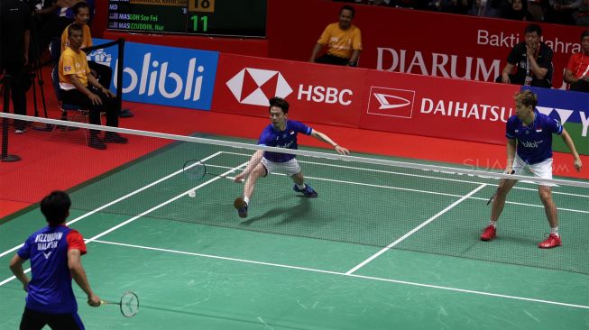 Pebulu tangkis ganda putra Indonesia Marcus Fernaldi Gideon dan rekannya Kevin Sanjaya Sukamuljo mengembalikan kok ke arah lawannya asal Malaysia Goh Sze Fei dan Nur Izzuddin dalam babak perempat final Daihatsu Indonesia Masters 2020 di Istora Senayan, Jakarta, Jumat (17/1). [Suara.com/Angga Budhiyanto]