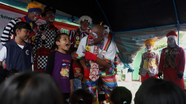 Sejumlah badut yang tergabung dalam komunitas Aku Badut Indonesia (ABI) menghibur anak-anak di pengungsian korban banjir Komplek IKPN Bintaro, Pesanggrahan, Jakarta Selatan, Minggu (5/1). [Suara.com/Angga Budhiyanto]