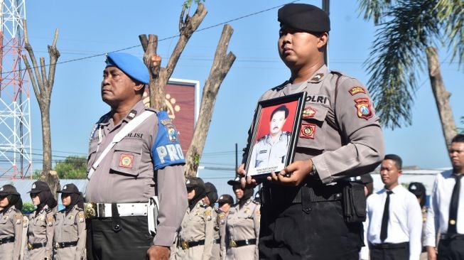 Personel Polri membawa foto AKP Heru Nurtjahyono saat upacara Pemberhentian Tidak Dengan Hormat (PTDH) di halaman Mapolresta Madiun, Jawa Timur, Jumat (17/1).  [ANTARA FOTO/Siswowidodo]