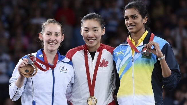 Michelle Li (tengah) berdiri di podium juara usai meraih medali emas tunggal putri Commonwealth Games 2014 di Glasgow, Skotlandia. Medali perak dan perunggu masing-masing diraih Kirsty Gilmour (Skotlandia/kiri) dan P V Sindhu. [AFP/Andrej Isakovic]