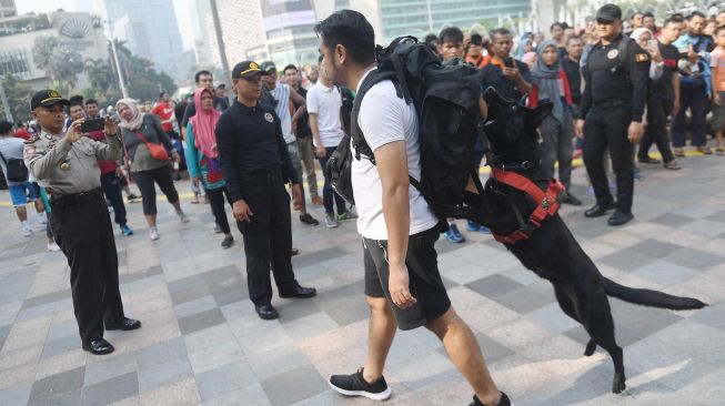 Anjing pelacak dari Unit K-9 Polri mengendus adanya bom yang dibawa oleh seseorang di dalam tasnya saat simulasi di kawasan hari bebas kendaraan bermotor atau car free day (CFD) di Jalan MH Thamrin, Jakarta, Minggu (19/1).  [ANTARA FOTO/Akbar Nugroho Gumay]
