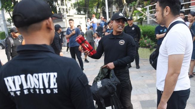 Seorang anggota Unit K-9 Polri menunjukkan bom yang berhasil diendus oleh anjing pelacak di antara masyarakat yang memadati hari bebas kendaraan bermotor atau car free day (CFD) saat simulasi di Jakarta, Minggu (19/1). [ANTARA FOTO/Akbar Nugroho Gumay]