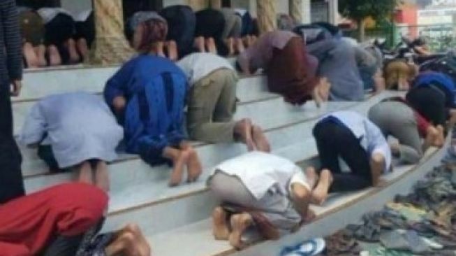 Foto orang sujud di masjid dengan arah berbeda. (Twitter/@NUgarislucu)