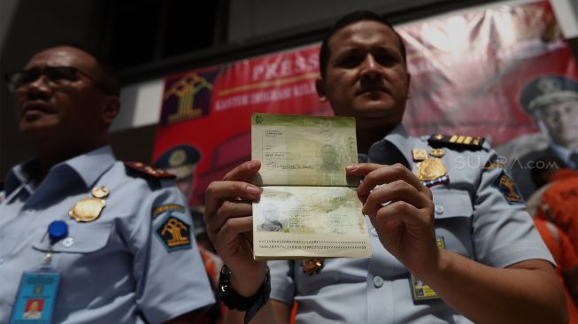 Kepala Imigrasi Jakarta Barat Noviyanto Sulastono (tengah) bersama jajarannya menunjukkan barang bukti saat rilis penangkapan orang asing di Kantor Imigrasi Jakarta Barat, Jakarta, Selasa (21/1). [Suara.com/Angga Budhiyanto] 