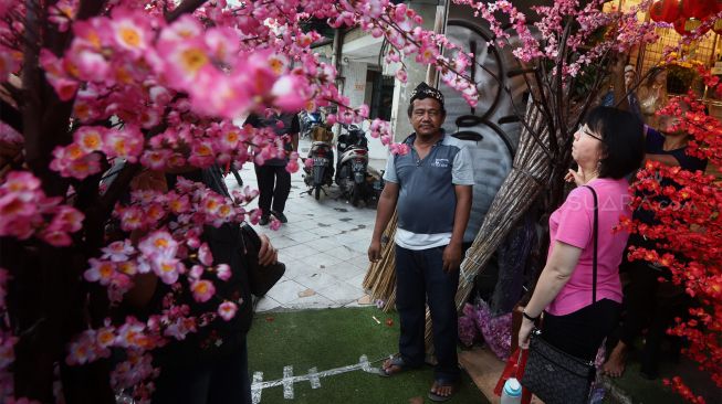 Calon pembeli melihat pohon bunga Meihua yang dijual di toko di kawasan pasar Asemka, Jalan Pintu Kecil, Jakarta Barat, Selasa (21/1). [Suara.com/Angga Budhiyanto]