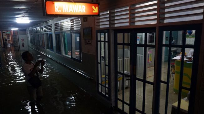 Warga berjalan di lorong Rumah Sakit Umum Daerah (RSUD) Kraton yang tergenang banjir di Pekalongan, Jawa Tengah, Senin (20/1/2020) malam. [ANTARA FOTO/Harviyan Perdana Putra]
