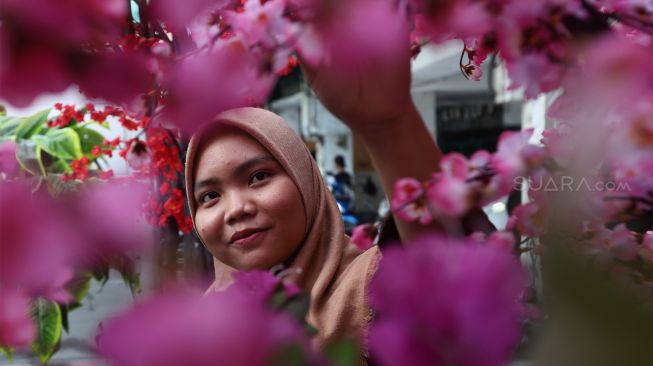 Pekerja menyelesaikan pesanan pohon bunga Meihua di toko di kawasan pasar Asemka, Jalan Pintu Kecil, Jakarta Barat, Selasa (21/1). [Suara.com/Angga Budhiyanto]
