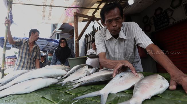 Pembeli memilih ikan bandeng di Pasar Rawa Belong, Jakarta Barat, Rabu (22/1). [Suara.com/Angga Budhiyanto]