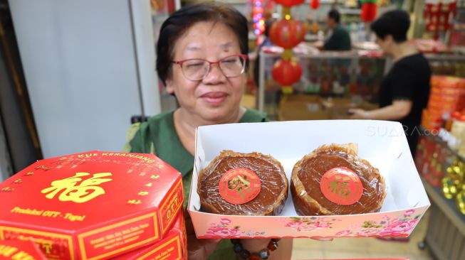 Pedagang menunjukan kue keranjang yang merupakan kue khas Imlek yang dijual di berbagai toko sepanjang jalan Surya Kencana, Bogor, Selasa (21/02).  [Suara.com/Alfian Winanto]