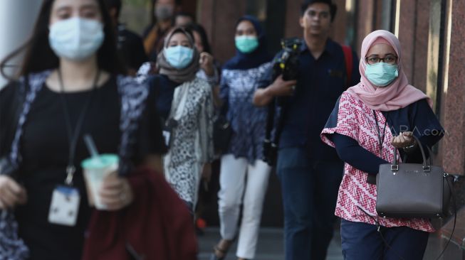 Sejumlah karyawan menggunakan masker saat keluar dari kantor Bank BRI, Jakarta, Kamis (23/1). [Suara.com.Angga Budhiyanto]