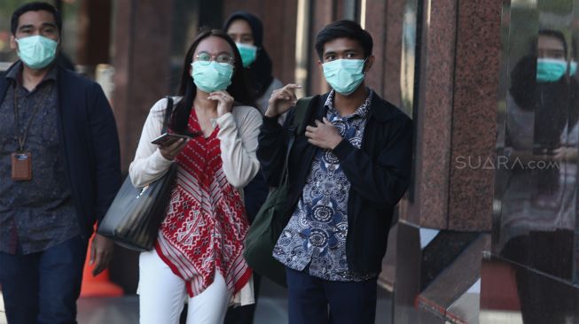 Sejumlah karyawan menggunakan masker saat keluar dari kantor Bank BRI, Jakarta, Kamis (23/1). [Suara.com.Angga Budhiyanto]