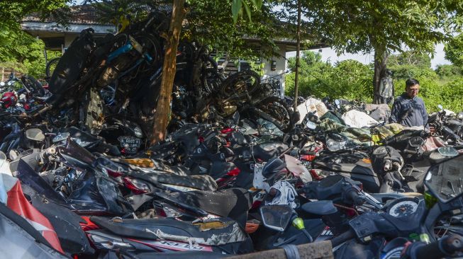 Warga melintasi kendaraan bermotor yang terparkir daerah Teluk Pucung di Bekasi, Jawa Barat, Kamis (23/1). [ANTARA FOTO/Fakhri Hermansyah]