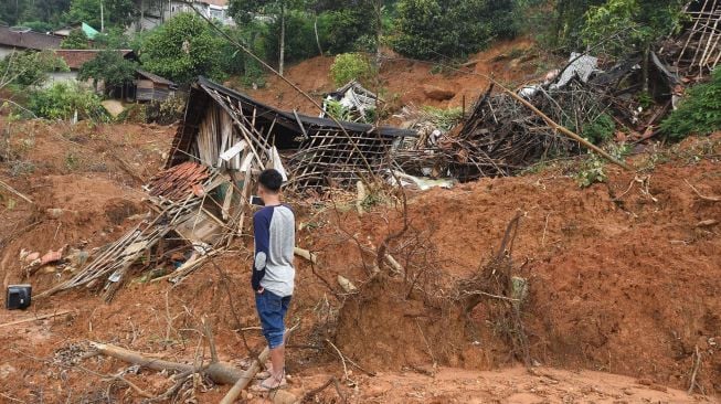 Warga memotret bangunan yang rusak tertimbun longsor dengan kamera ponsel di Kampung Cigobang, Desa Banjarsari, Lebak, Banten, Jumat (24/1). [ANTARA FOTO/Asep Fathulrahman]